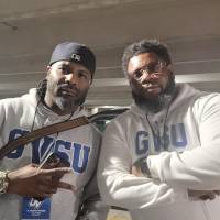 Two alumni in GVSU sweatshirts pose for a photo.